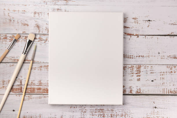 istock Colorful creative table with blank canvas for sketches and paintbrushes set on white wooden table, top view, copy space, flat lay style, drawing class education 1225355203
