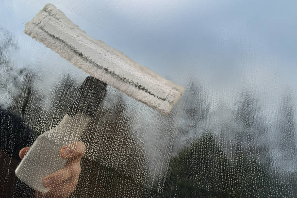 istock Caucasian man washing glass with microfiber window washer. 1225357745