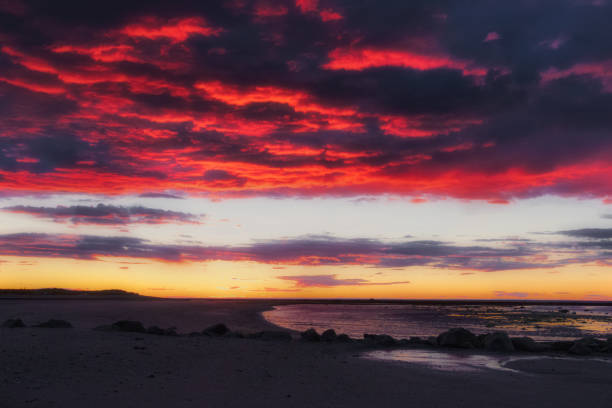 istock Dark red and black cloudy sky at sunset on sand and rocks beach 1225359178