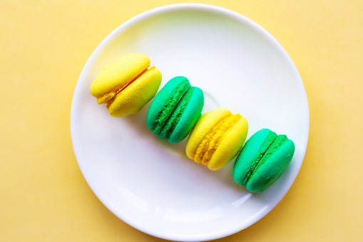 Yellow and green sweet tasty macaroons on the plate. Flat lay, top view