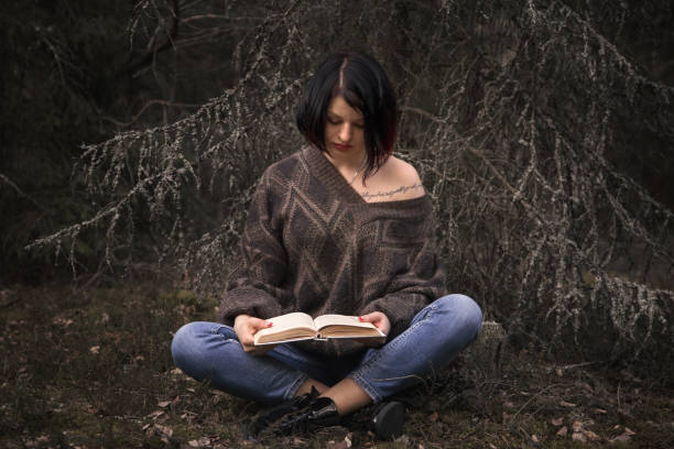 istock young woman reading a book in nature 1225362055