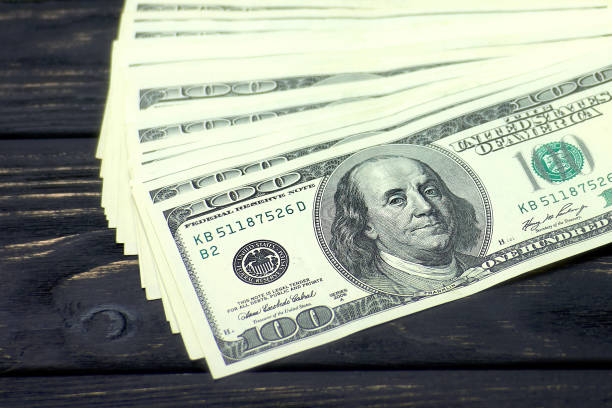 istock Stack of hundred dollars close up on black wooden table. 1225366350