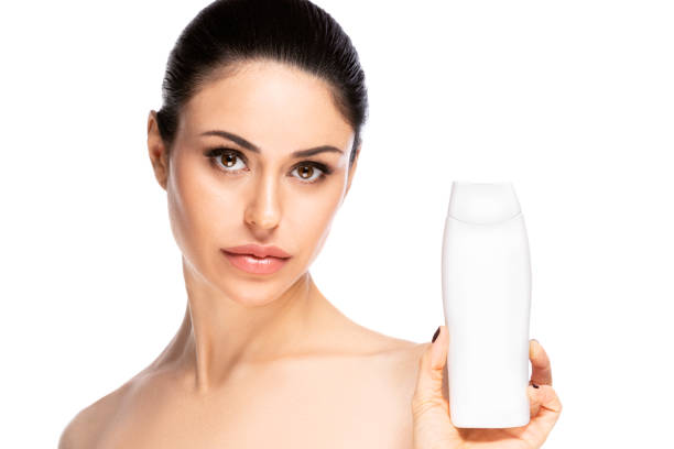 istock Beautiful woman holding white empty shampoo tube on white background 1225367199