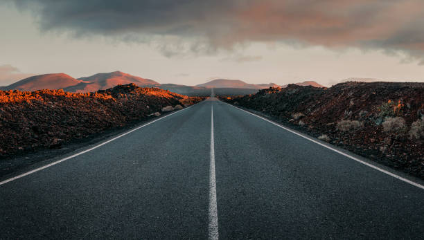 Empty road through the volcanic field Empty road through the volcanic field at the sunrise with copy space long stock pictures, royalty-free photos & images
