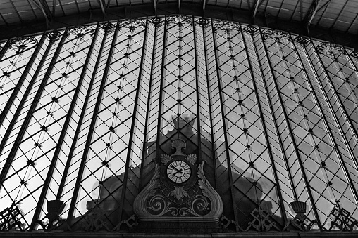 Clock at the side facade of the old Atocha station, the largest railway station in Madrid. Monochrome.