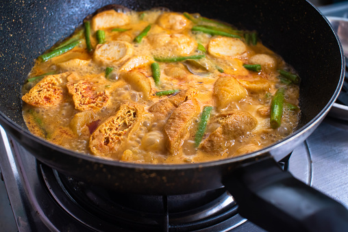 Close-up of boiling curry with deep fried tofu, meat balls and Chinese long bean cooking in hot pan Asian Chinese cuisine.