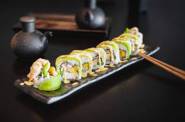 rotolo di sushi di granchio croccante con asparagi, mango avvolto in avocado fresco sottile e salsa agrodolce - sushi chopsticks sushi bar food foto e immagini stock