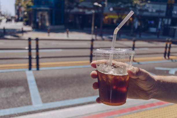istock mans hand holding iced coffee cup on sunny hot day 1225382225