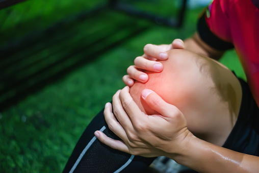 Male soccer player suffering from knee Injury on field.