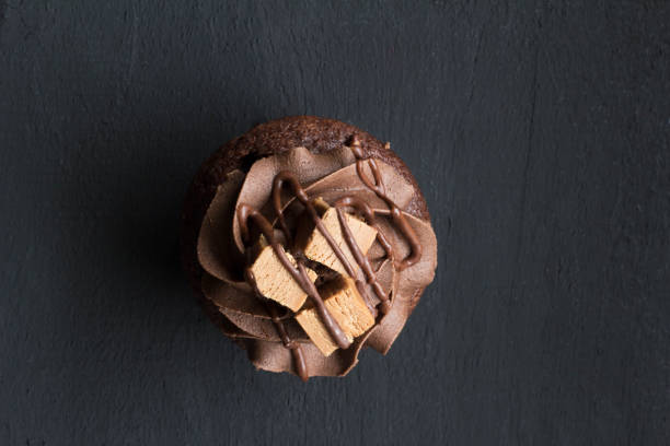 istock Top view chocolate cup cake isolated on rustic black background - overhead photo with space for text 1225387975