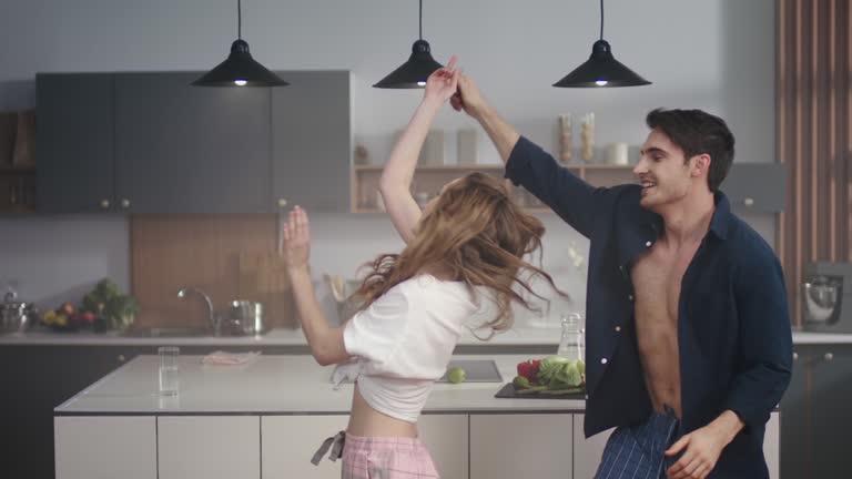 Young couple dancing together at home kitchen. Happy friends having fun indoors.