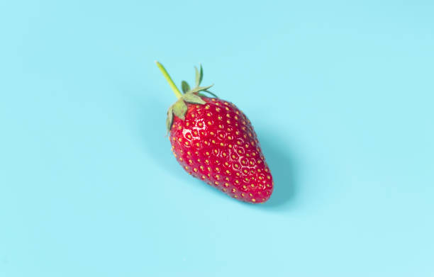 istock Single , fresh, red strawberry on light blue background 1225390772