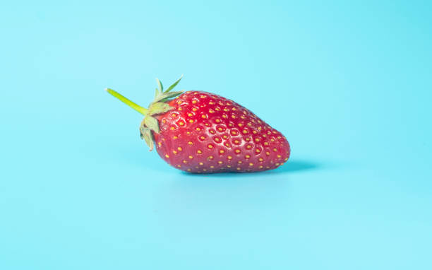 istock Single , fresh, red strawberry on light blue background 1225390820