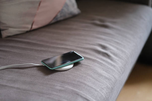 istock one smartphone on wireless charger on sofa. 1225393281