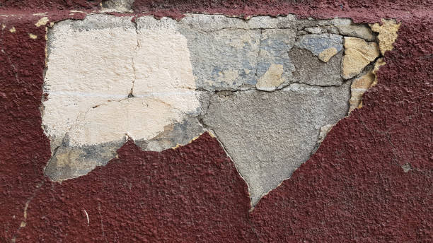 istock Ruined dark red wall structure with cracks and rough textured plaster surface 1225394717