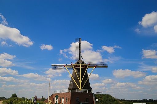 Beesel, Netherlands - May 17. 2020: View on isolated typical dutch windmill (Molen de grauwe beer) in rural landscape against blue sky with cumulus clouds