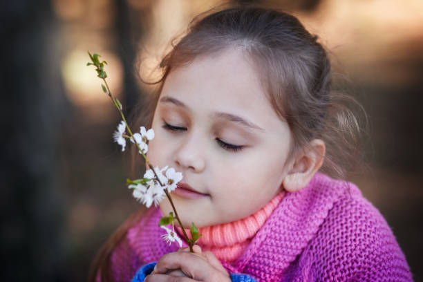 istock little girl sniffs cherry flowers 1225399784