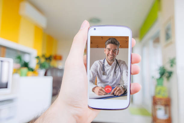 istock Man having mobile video call with smiling young doctor at home 1225400411
