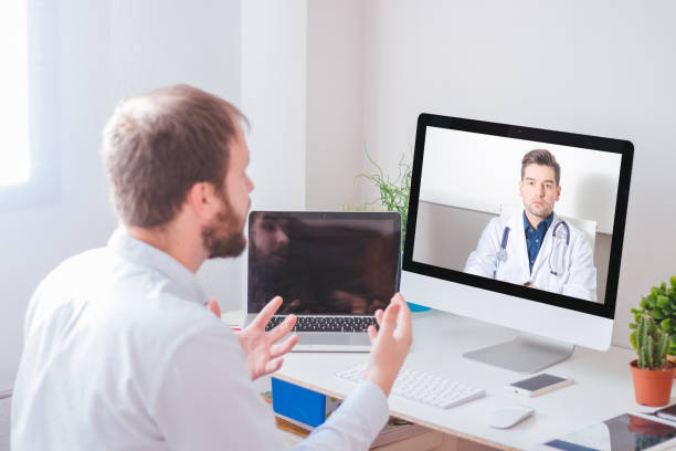 istock Man in front of computer videoconferencing with doctor at home. 1225400412