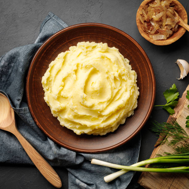 istock Mashed potatoes, boiled puree in a brown plate on a black slate background. 1225403615