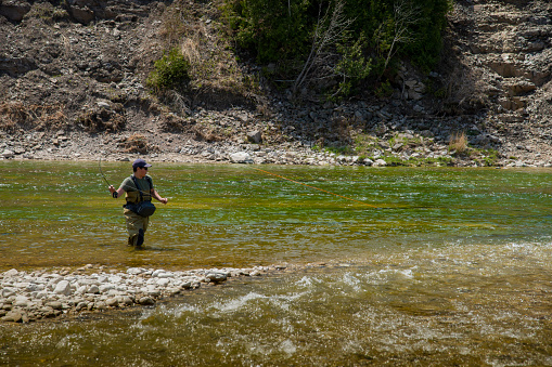 A teen fly-fisher casting on a beautiful tributary river of  Lake Huron.