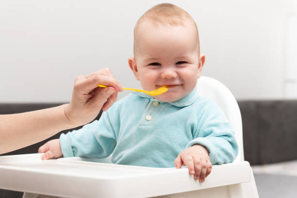 istock Mom Feeds Baby With Fruit Puree At Home 1225404841