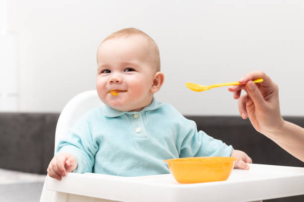 istock Mom Feeds Baby With Fruit Puree At Home 1225404842
