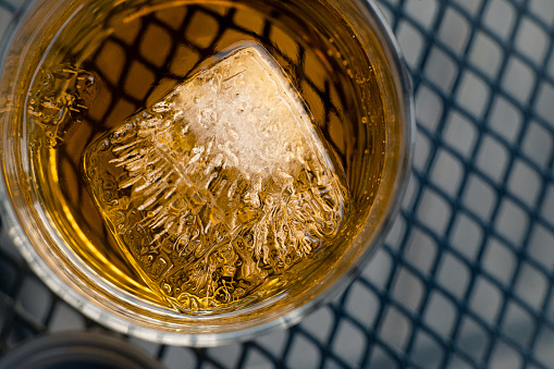 Beautiful abstract shot of the details in a large ice cube in iced tea on a warm summer night