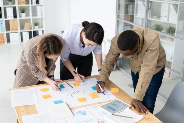 istock Three intercultural colleagues with highlighters bending over table with papers 1225410096