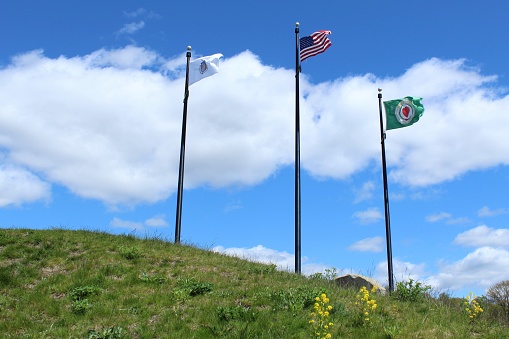 the Worcester aka, Massachusetts, and Usa flags on pole before a cloudy sky