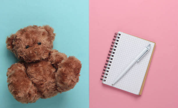 istock flat lay composition of a teddy bear, notebook with pen on a blue-pink pastel background. Top view 1225410466