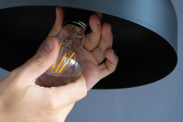 istock Close-up. A hand changes a light bulb in a stylish loft lamp. Spiral filament lamp. Modern interior decor. 1225411134