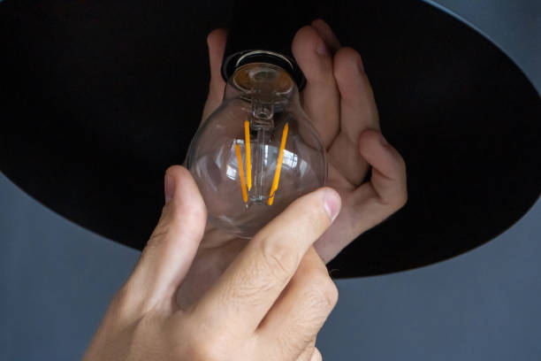 istock Close-up. A hand changes a light bulb in a stylish loft lamp. Spiral filament lamp. Modern interior decor. 1225411244