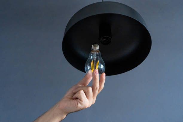 istock Close-up. A hand changes a light bulb in a stylish loft lamp. Spiral filament lamp. Modern interior decor. 1225411745