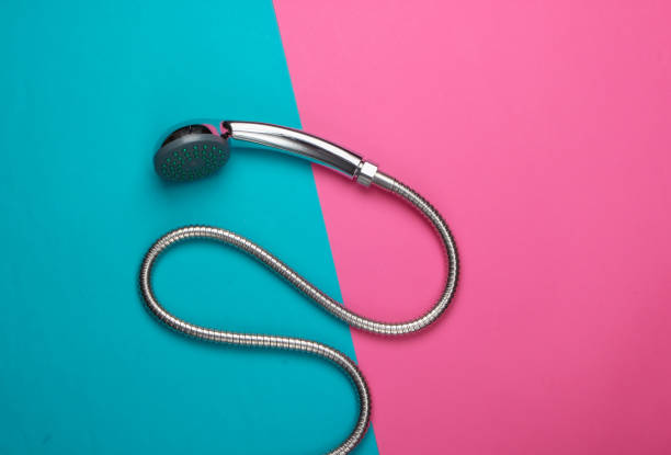 Shower head for the bathroom with a hose on blue pink background. Top view