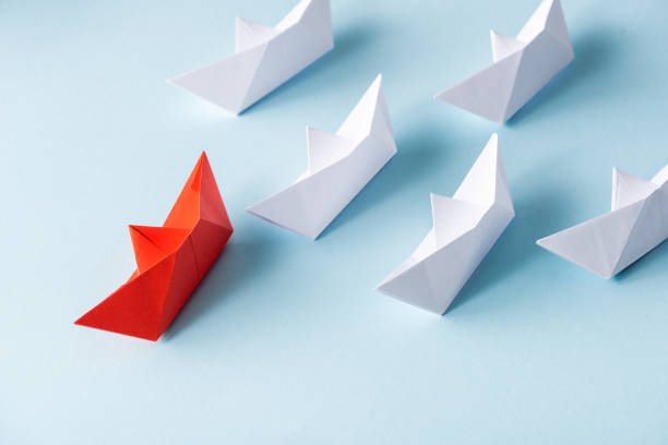 istock High angle view of unique red paper boat among white on blue 1225414435