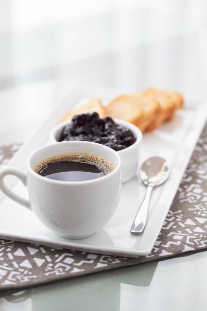 A cup of coffee and toasts with cranberries jam on white background.
