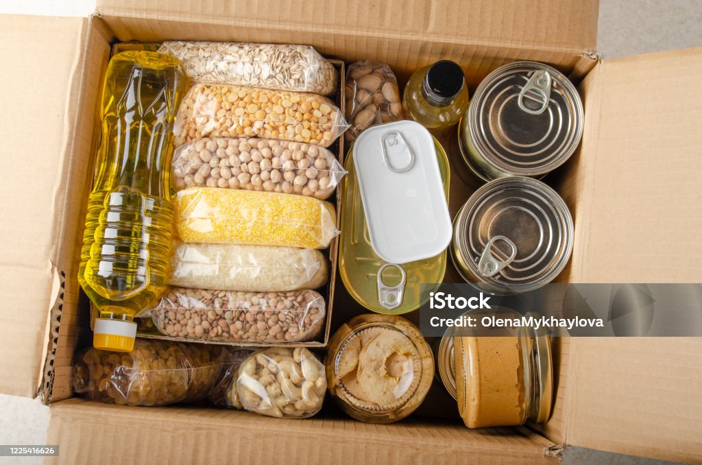 Flat lay view at uncooked foods in carton box prepared for disaster emergency conditions or giving away Food Stock Photo