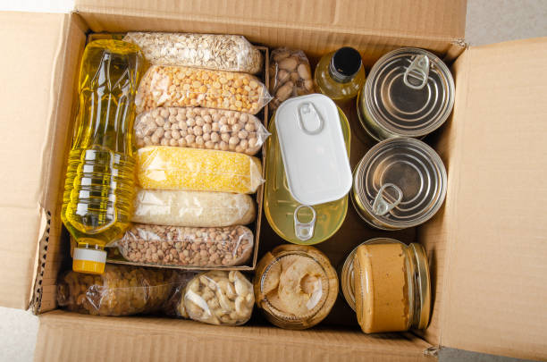 flat lay view at uncooked foods in carton box prepared for disaster emergency conditions or giving away - non perishable imagens e fotografias de stock