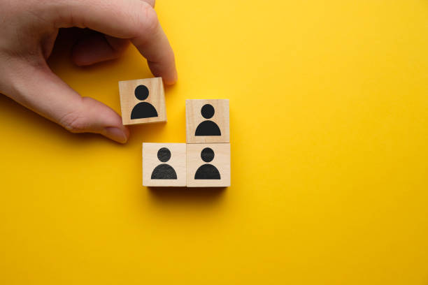 istock Fired concept - hand holds wooden block with abstract worker on a yellow background. 1225418005