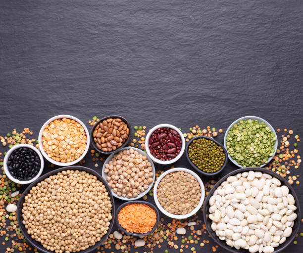 istock Legumes assortment in various bowls on black stone background 1225420079