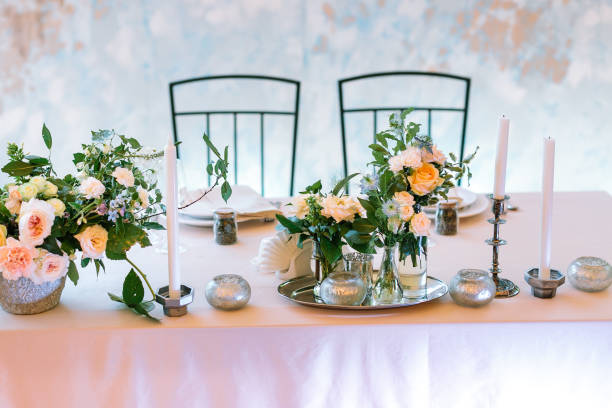 la table de mariage centrale du dîner de bienvenue - un endroit pour la mariée et le marié dans les couleurs tendres et pastel, décorée avec des bougies et des compositions de fleurs avec l’illumination blanche - just married concepts ideas place setting photos et images de collection