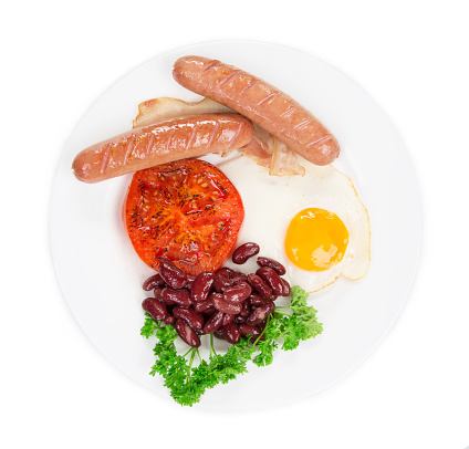 Traditional Full English Breakfast with fried eggs sausage beans is like an haute cuisine. Isolated in a white background. Close-up.