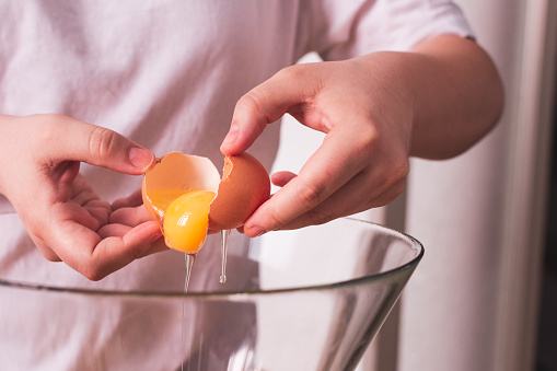 person breaking an egg into a bowl