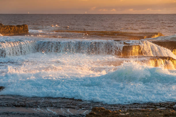 istock Ocean coastline scene with waves crushing over rocks at sunrise 1225426543