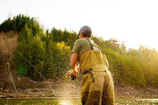 A fly-fisherman casting double-handed Spey rod in warm afternoon light.