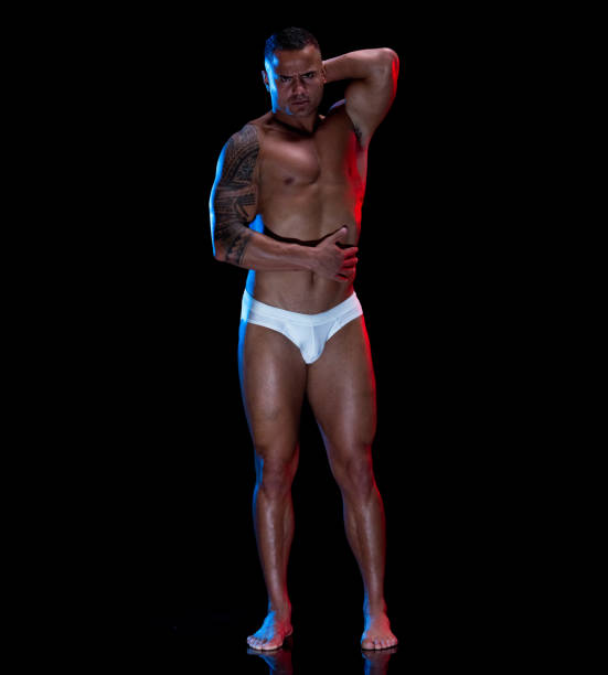 istock Pacific islander ethnicity young male stripper standing in front of black background wearing racing briefs 1225428764