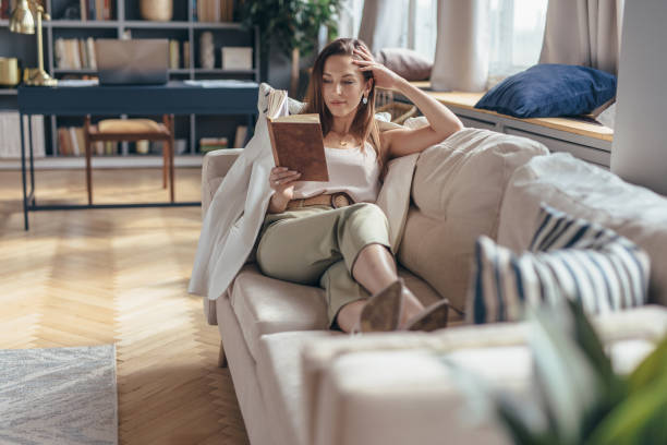istock Woman lying on sofa and reading book at home 1225430949