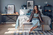 Elegant young woman sitting in bedroom. Home interior