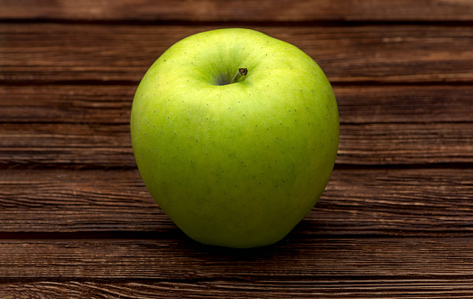 Green apple on dark brown wooden background. Summer fruits. Natural vitamins. Healthy food.